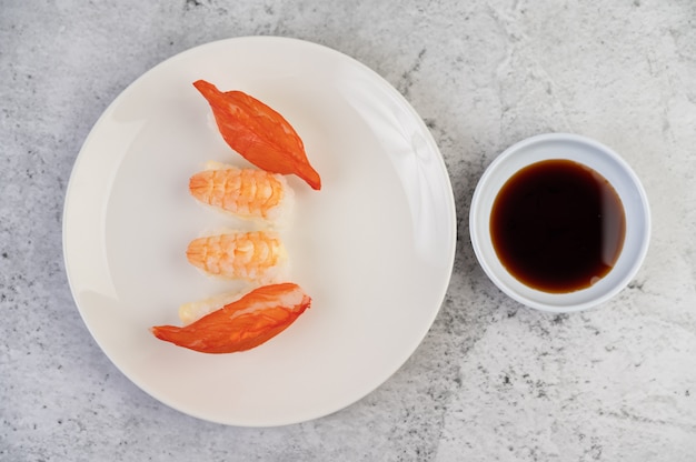 Free Photo sushi is on a plate with dipping sauce on a white cement floor.