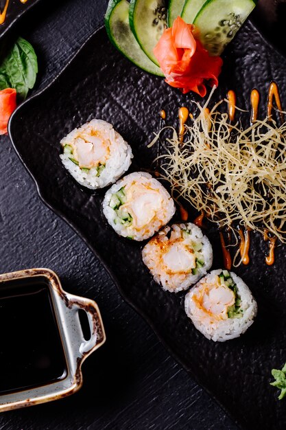 Sushi nori with soy sauce inside black plate.