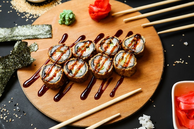 Sushi roll set on the desk topped with sauce top view