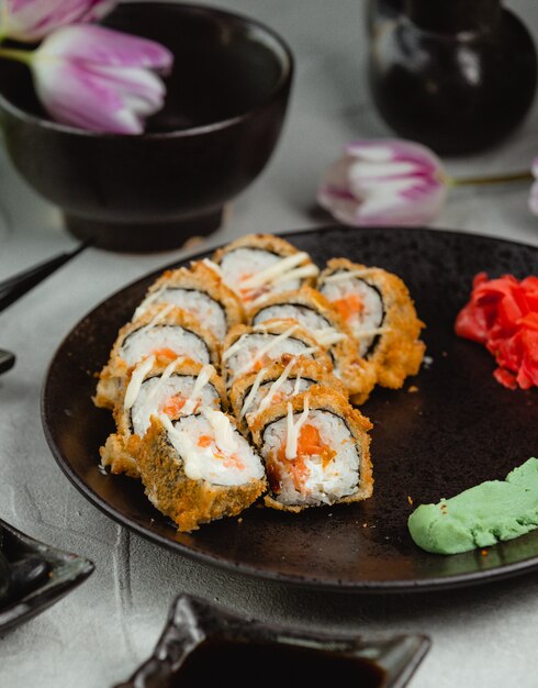 Sushi rolls in blac plate with tulips around.