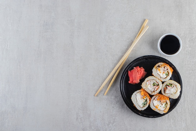 Sushi rolls, soy sauce, wasabi and pickled ginger on stone table.