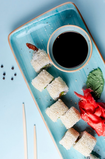 Free photo sushi rolls topped with sesame and side sauce