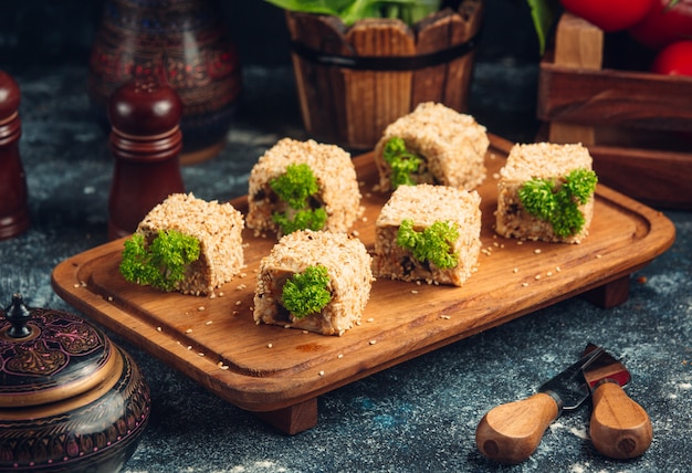 Free photo sushi rolls with green pistachio on a wooden board.