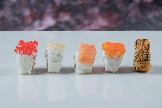 Sushi rolls with mixed ingredients isolated on white table.