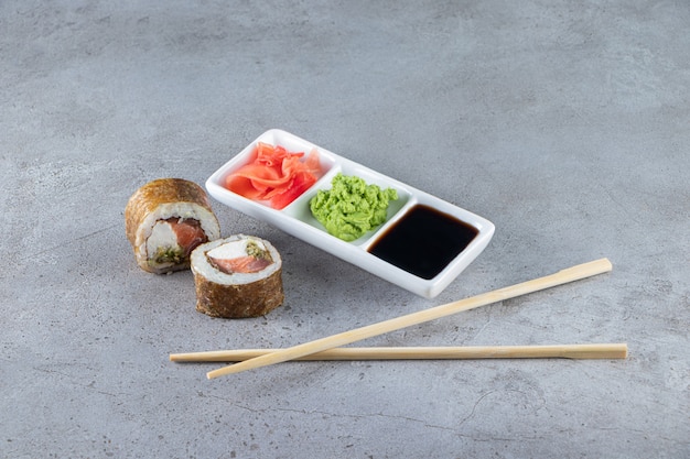 Sushi rolls with tuna fish, wasabi, ginger and soy sauce on stone background. 