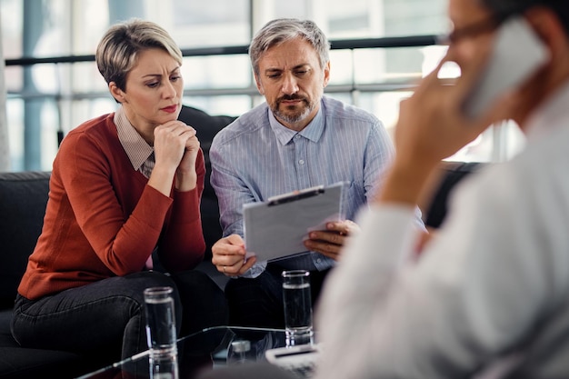 Free photo suspicious couple going through insurance agreement while being on a meeting with their agent