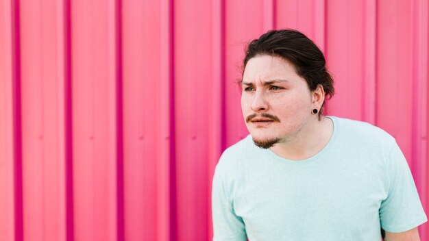 Suspicious man standing against pink corrugated metal sheet