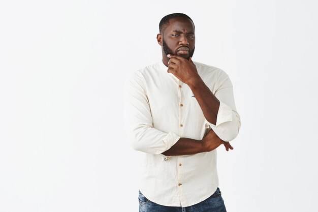 Suspicious young guy posing against the white wall