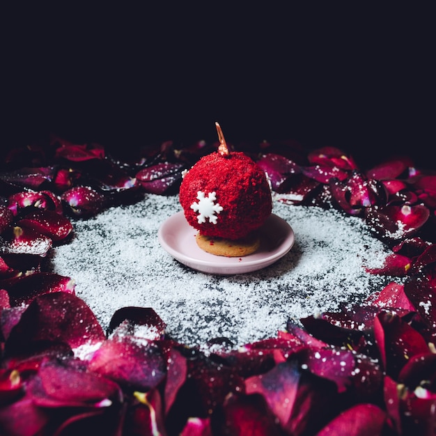 Free Photo sweet ball covered with red powder stands in the circle of red rose petals