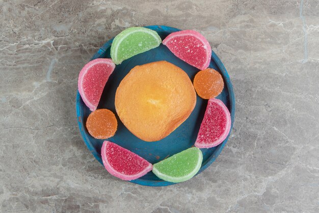 Sweet cake and marmalade candies on blue plate