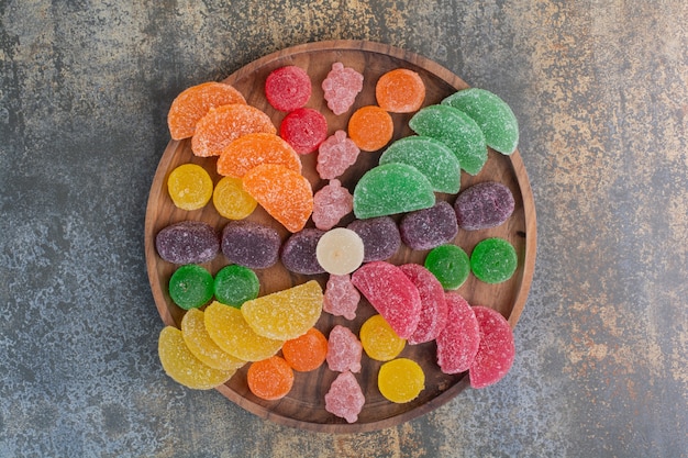 Free photo sweet colorful jelly candy on wooden plate . high quality photo