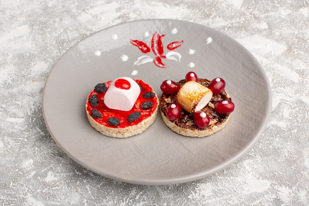 Free photo sweet cookies with cream and dogwoods inside plate on grey