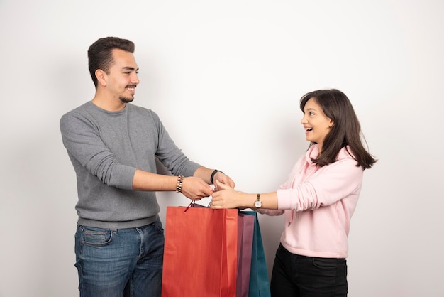 Sweet couple carrying shopping bags on white.