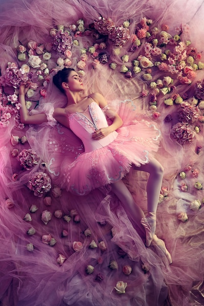 Free Photo sweet dreams. top view of beautiful young woman in pink ballet tutu surrounded by flowers. spring mood and tenderness in coral light.