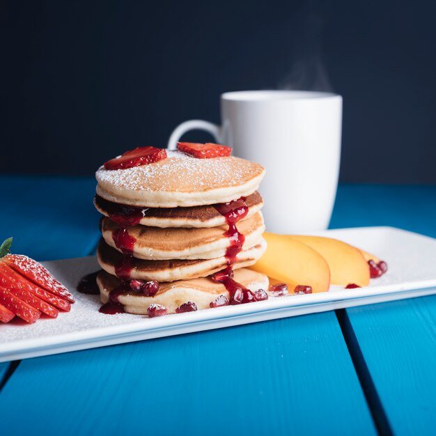 Sweet homemade stack of pancakes with syrup for breakfast on blue desk