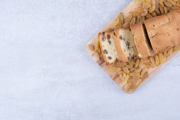 Sweet loaf with bunch of raisins on wooden board.