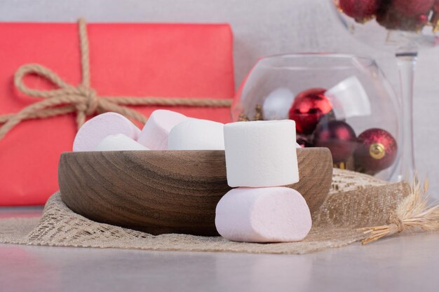 Sweet marshmallows on wooden board on burlap