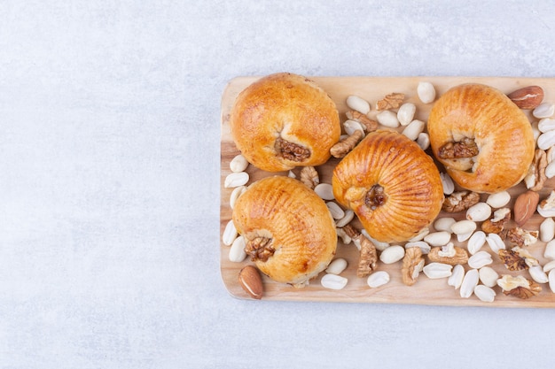 Free photo sweet pastries with kernels on wooden board with various nuts