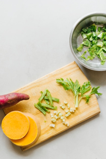 Sweet potato; sliced pumpkin and celery on wooden chopping board