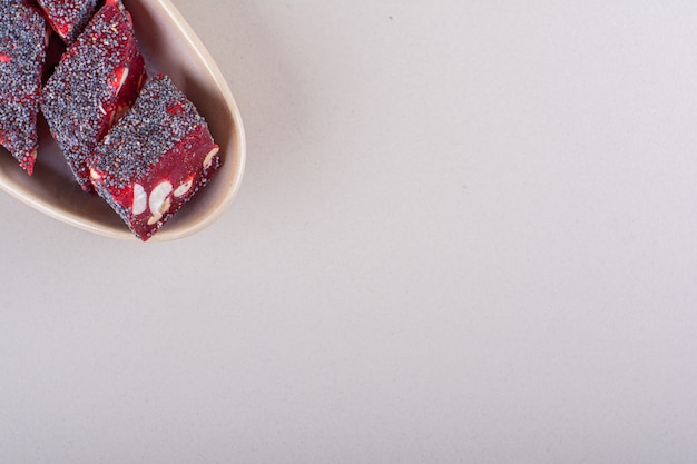 Sweet red candies with nuts in beige bowl on white background. High quality photo