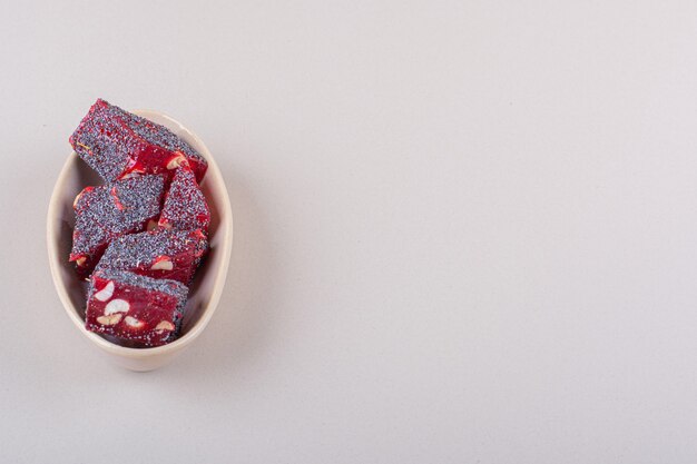 Sweet red candies with nuts in beige bowl on white background. High quality photo