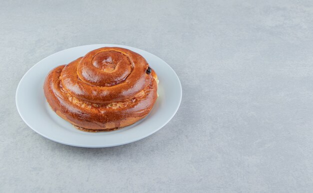 Sweet swirl bun on white plate. 