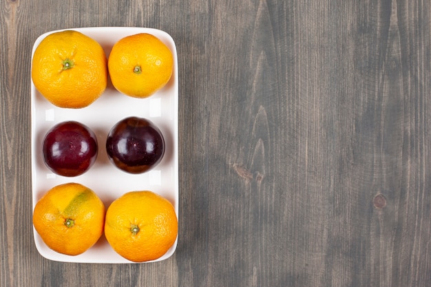 Free Photo sweet tangerines with plums on a wooden table. high quality photo