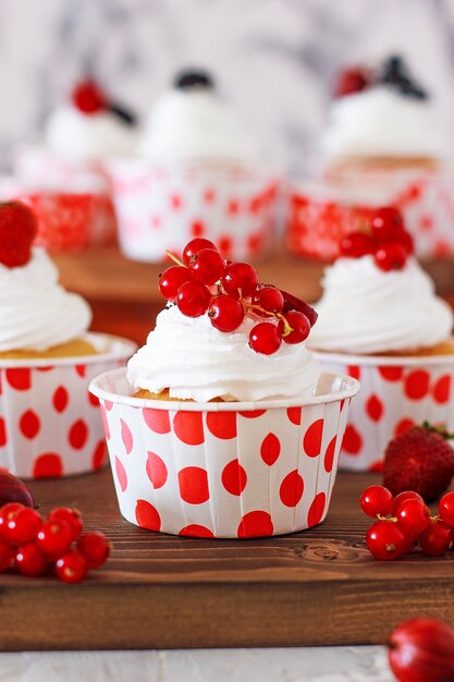 Sweet vanilla cupcakes with berry jam filling and cheese cream, decorated with summer berries