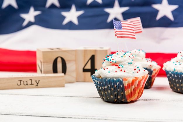 Free photo sweet whipped cream cupcake with american flags and wooden cubes