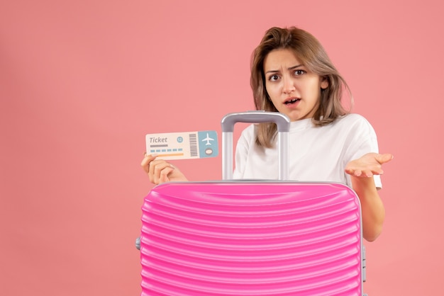 Free Photo sweet young woman holding ticket behind pink suitcase