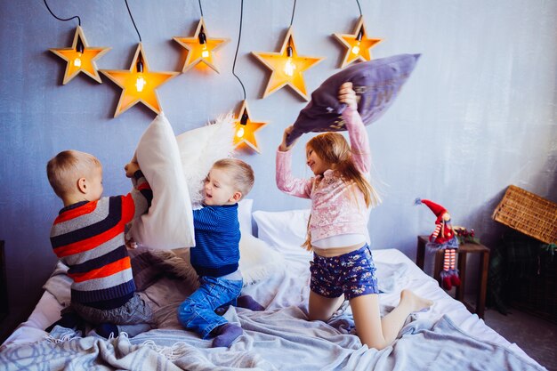 The sweety girl and boys playing and jumping on the bed