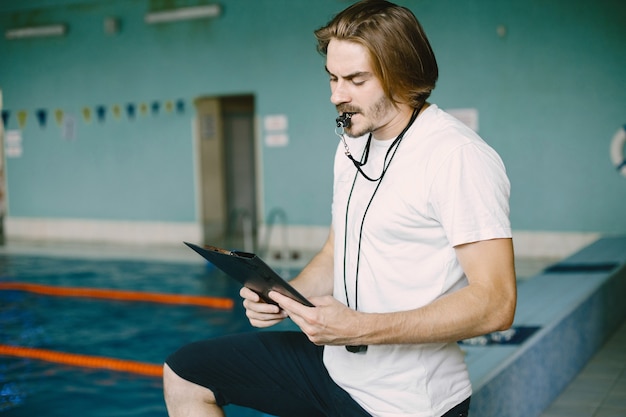 Free Photo swimming coach standing by the pool. checking swimming records. holding clipboard.