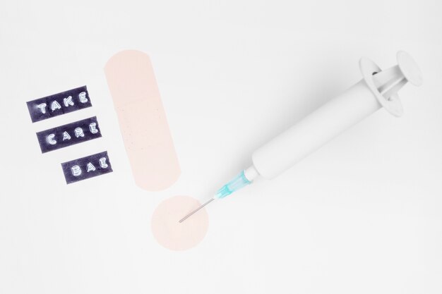 Syringe and bandage with take care message on white background