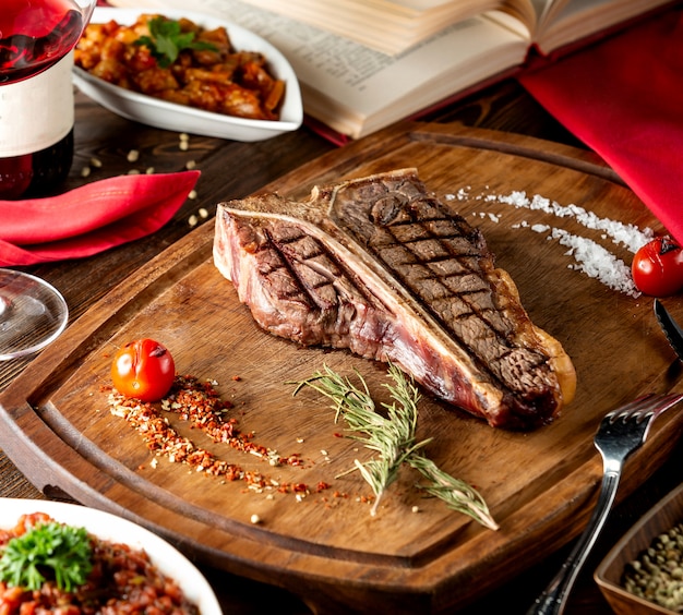 T-bone steak served in wooden board with slat rosemary