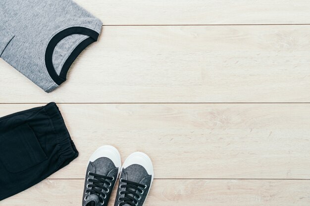 T-shirt with pants and shoes on wooden background