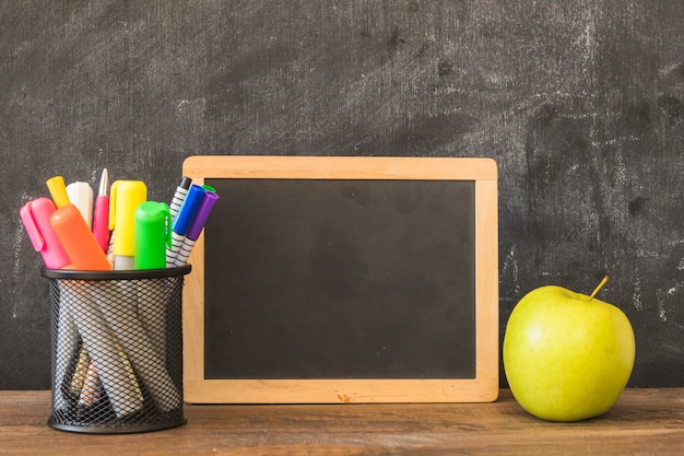 Free Photo table with pencil cup blackboard frame and apple