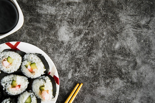 Table with sushi rolls, soy sauce and wooden chopsticks