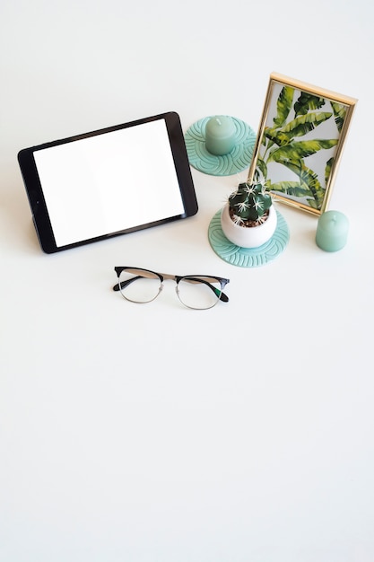 Free photo table with tablet near photo frame, houseplant and eyeglasses