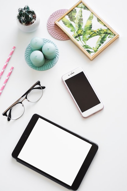 Free photo table with tablet near smartphone, photo frame, candles and eyeglasses