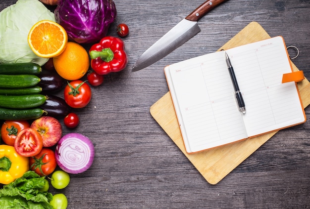 Table with vegetables, a knife and a notebook