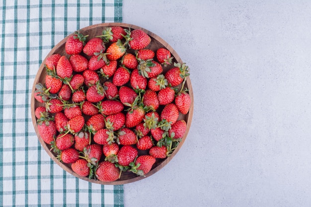 Tablecloth under a large bowl full of strawberries on marble background. High quality photo