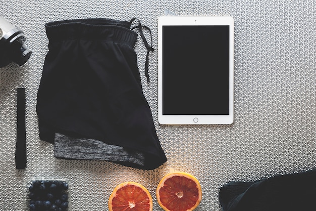 Tablet near shorts and fruits