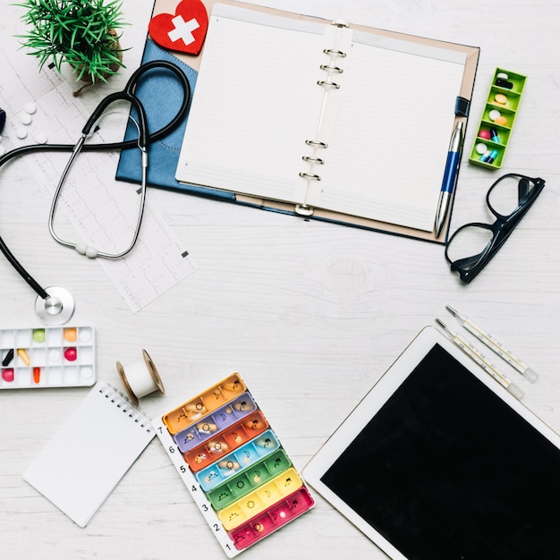 Tablet and notebook near medical supplies