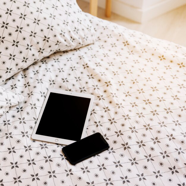 Tablet and smartphone on bed