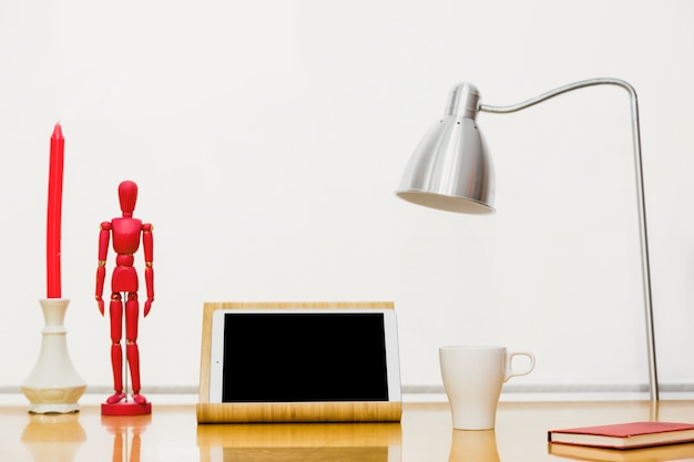 Free photo tablet with wooden mannequin and notebook on table