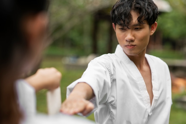 Free photo taekwondo training taking place outdoors in nature with two people