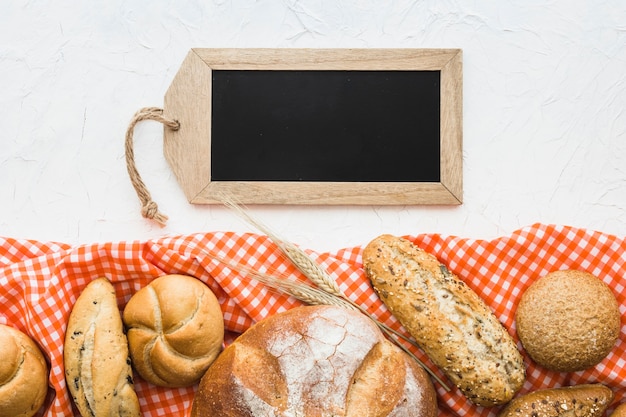 Free Photo tag-shaped chalkboard near bread and cloth