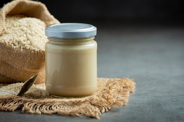 Tahini and sesame seeds on dark background