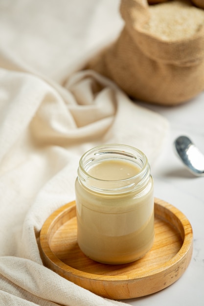 Tahini and sesame seeds on marble background