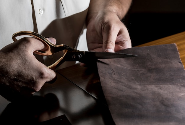 Tailor cutting leather with scissors